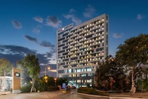 Un hotel de varios pisos con un diseño moderno, que destaca por su entrada principal y fachada iluminada.