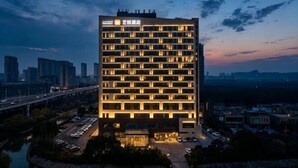 A high-rise hotel with multiple floors, a prominent entrance, and a view of the cityscape. - Yancheng Baolong Yiyue Select Hotel (Yancheng)