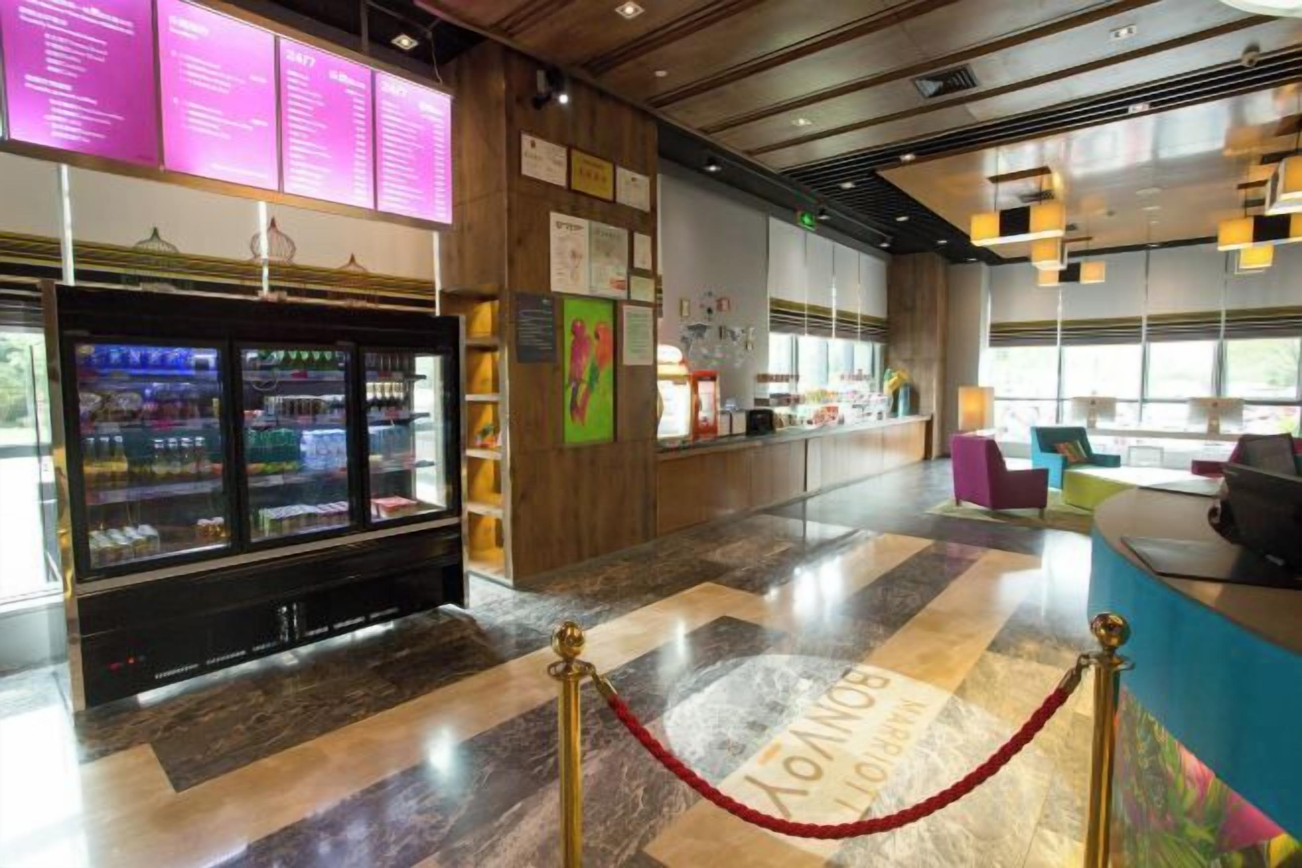 Un vestíbulo de hotel con una recepción, un refrigerador con bebidas y un piso de mármol.