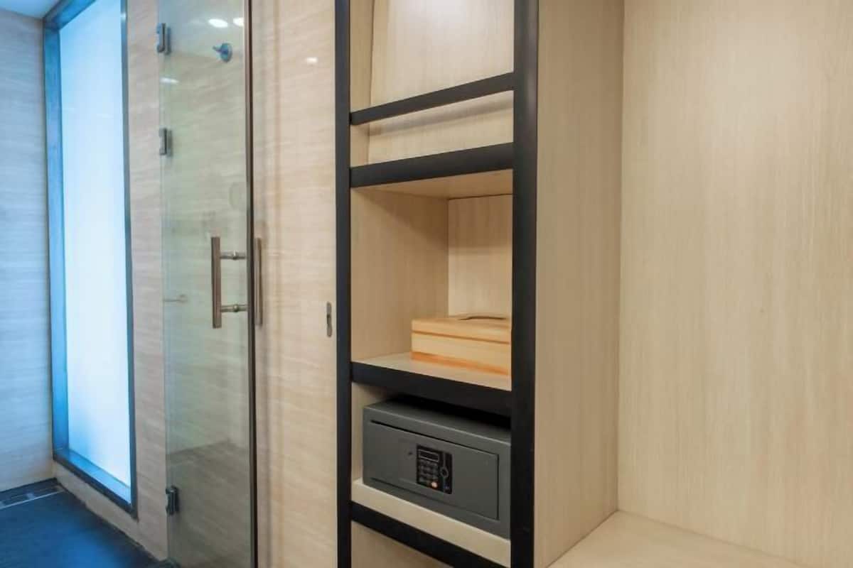 Une salle de bain moderne dotée d’une douche à parois de verre, d’un meuble-lavabo en bois avec un verrou intégré et d’un sol carrelé aux couleurs claires.