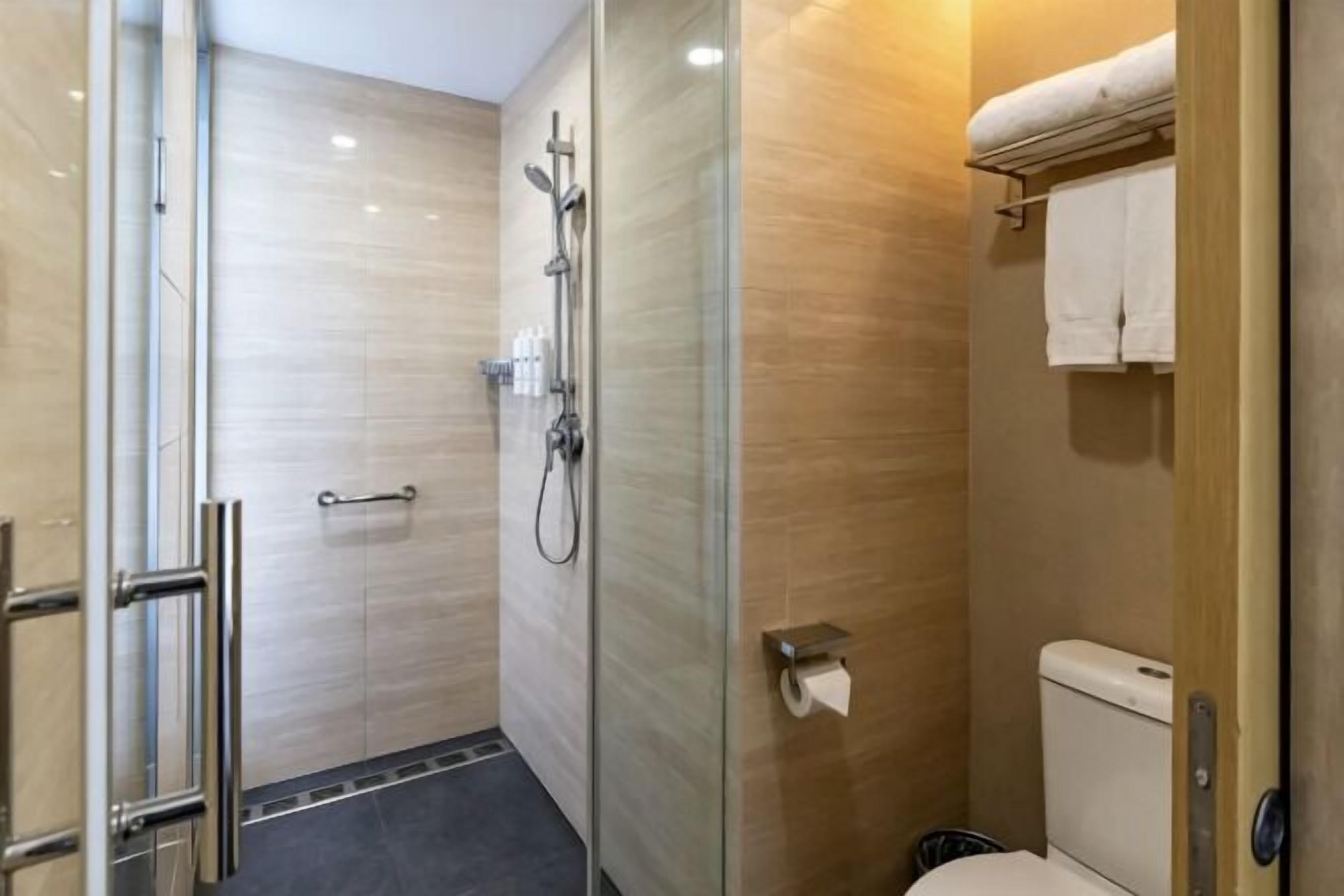 A bathroom with a glass shower enclosure, a toilet, and a towel rack.