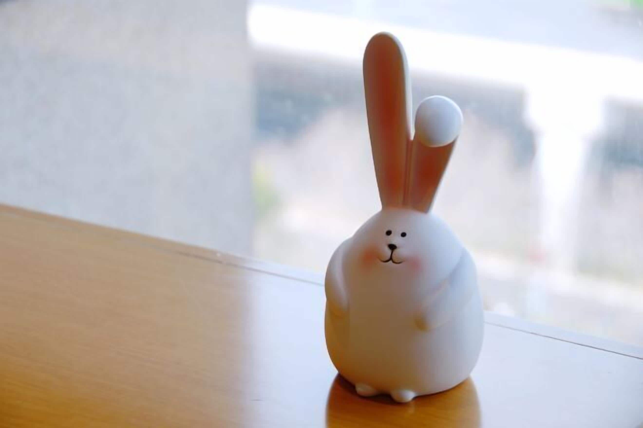 Una pequeña figura de conejo blanca sobre una superficie de madera.