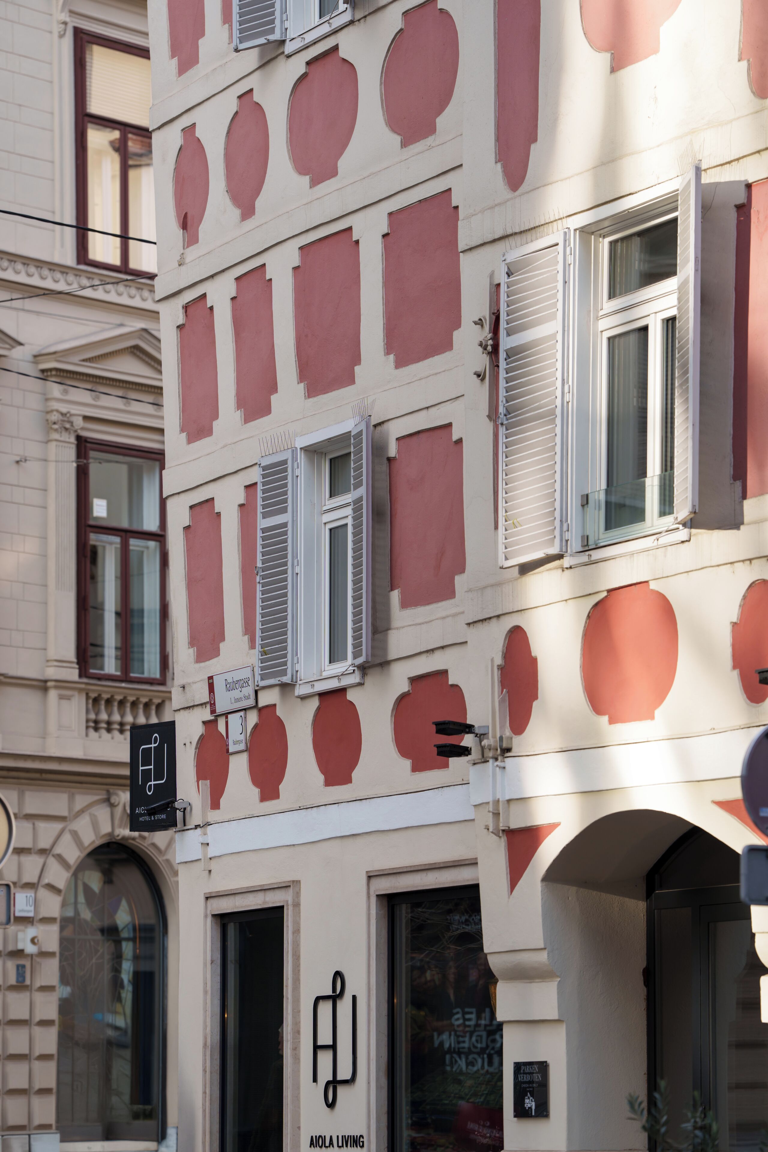 A building facade with multiple windows, some with shutters, and a sign indicating a hotel and store.