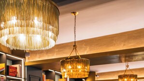 A modern lounge area with blue seating, a round table with glasses and a candle, and bookshelves in the background. - Aiola Living Boutique Hotel Graz (Graz)