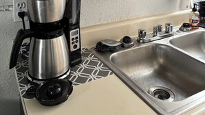 Una cocina con cafetera, pileta y armarios de madera.