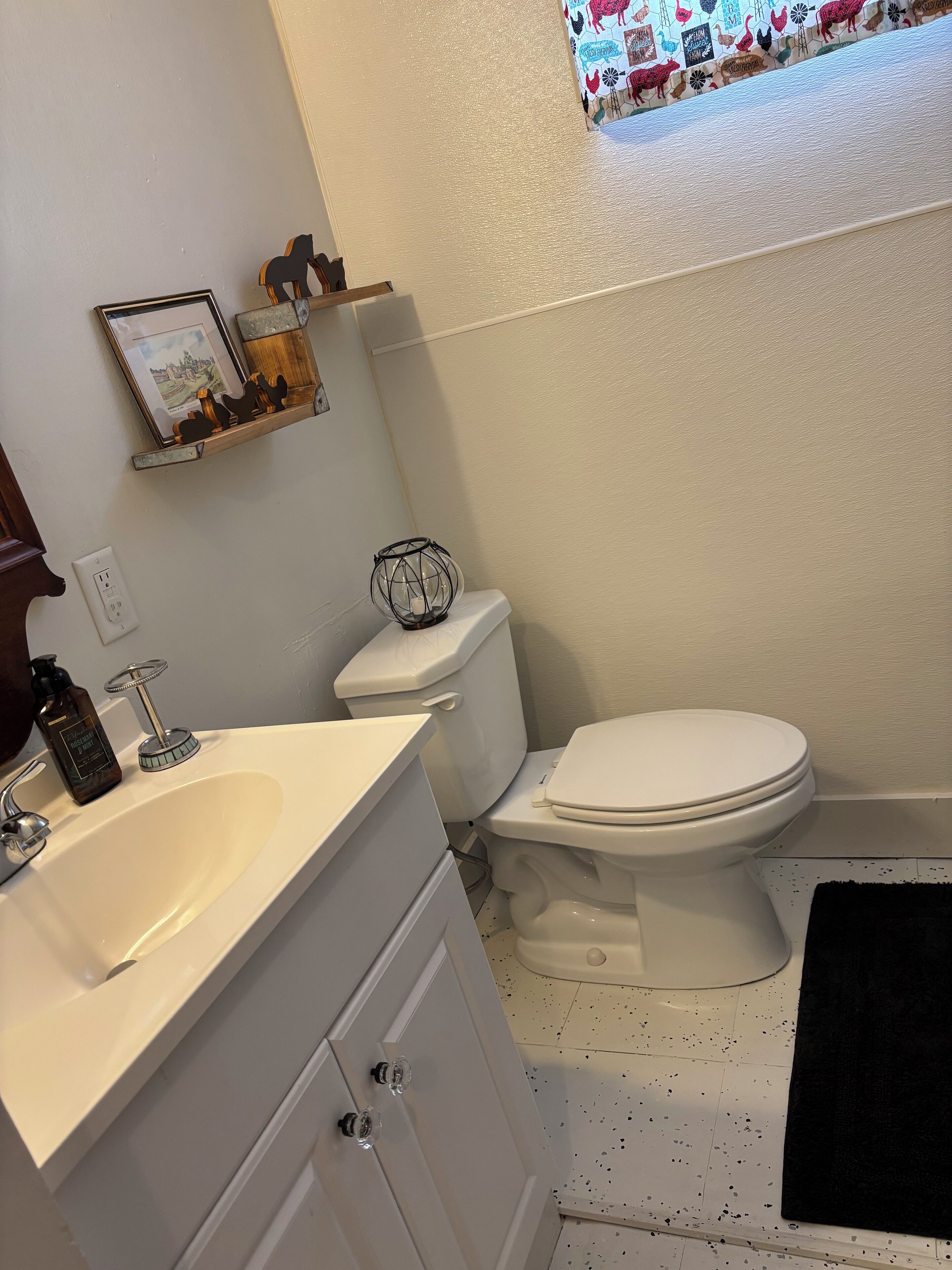 A bathroom with a white sink, toilet, and a shelf with decorative items.
