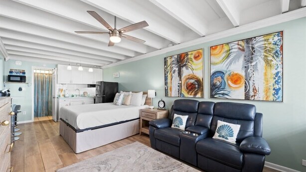 A modern bedroom with a bed, a reclining chair, a ceiling fan, and artwork on the wall. - Beachfront Studio, Sleeps 2, Pool (Panama City Beach)