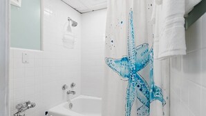 A bathroom with a bathtub, a shower curtain with a starfish design, and a towel rack. - Beachfront Studio, Sleeps 2, Pool (Panama City Beach)