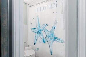 A bathroom with a shower curtain featuring a starfish design and the text 'LET'S FLOAT AWAY'.