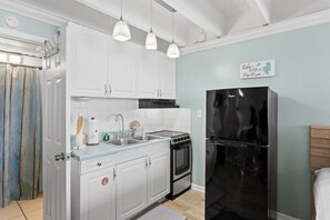 A kitchen with white cabinets, a black stove, and a black refrigerator.