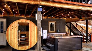 A hot tub with a wooden exterior and a stone interior, a wooden deck with railings, and a staircase leading to a covered area. - Amber Hills Lodge: Sauna,Golf Sim,Hot Tub,Theatre (Lancaster)