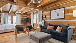 A log cabin interior with a bed, sofa, ottoman, and a framed deer head picture on the wall. - Amber Hills Lodge: Sauna,Golf Sim,Hot Tub,Theatre (Lancaster)