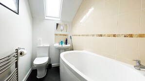 A bathroom with a toilet, sink, and bathtub. - Cosy Family One Bedroom flat with private Kitchen (Sutton)