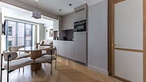 Una cocina moderna con electrodomésticos integrados, un comedor con mesa y sillas redondas, y vistas al exterior.