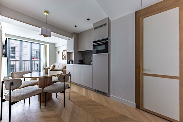 Una cocina moderna con electrodomésticos integrados, un comedor con mesa y sillas redondas, y vistas al exterior.