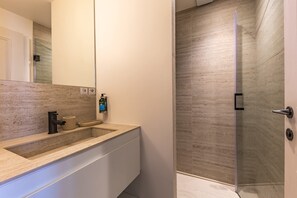 A modern bathroom with a large mirror, a sink, and a shower area.