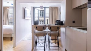 A modern kitchen with a dining area, a large window, and a view of the city. - Opera - One Bedroom Balcony (Paris)