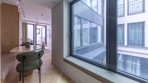 A modern interior with a large window, a dining area, and a view of a building outside.