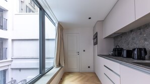 A narrow kitchen with a window, a door, and a view of an outdoor balcony.
