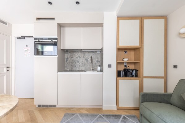 Una cucina compatta con elettrodomestici integrati, un pensile in legno e un tappeto grigio.