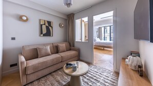 A modern living room with a sofa, a round coffee table, and a flat-screen TV mounted on the wall. - Opera - One bedroom apt. with balcony in Paris (Paris)