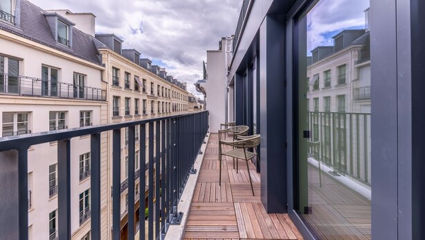 A balcony with a wooden floor, metal railing, and two wicker chairs. - Opera - One bedroom apt. with balcony in Paris (Paris)