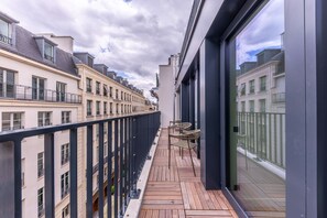 A balcony with a wooden floor, metal railing, and two wicker chairs. - Opera - One bedroom apt. with balcony in Paris (Paris)