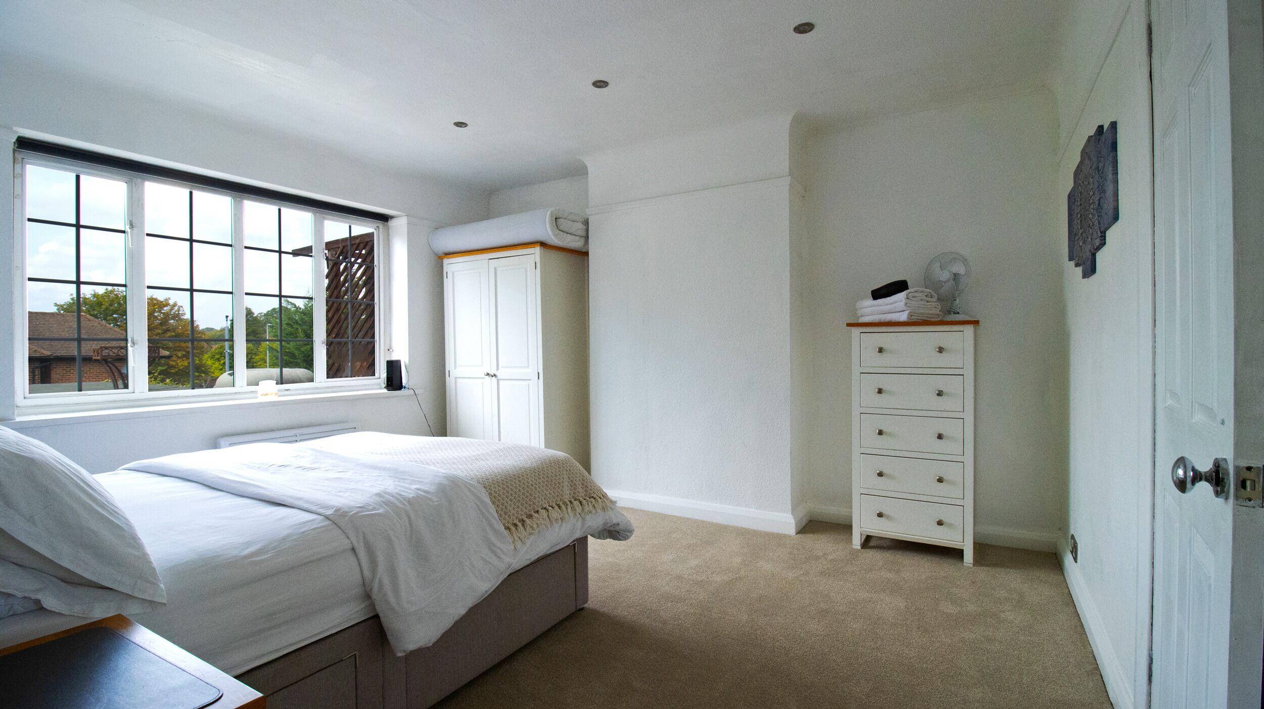 Un dormitorio con cama, cómoda, ventana y puerta.