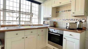 A kitchen with white cabinets, a sink, a window, a microwave, a toaster, and an oven.