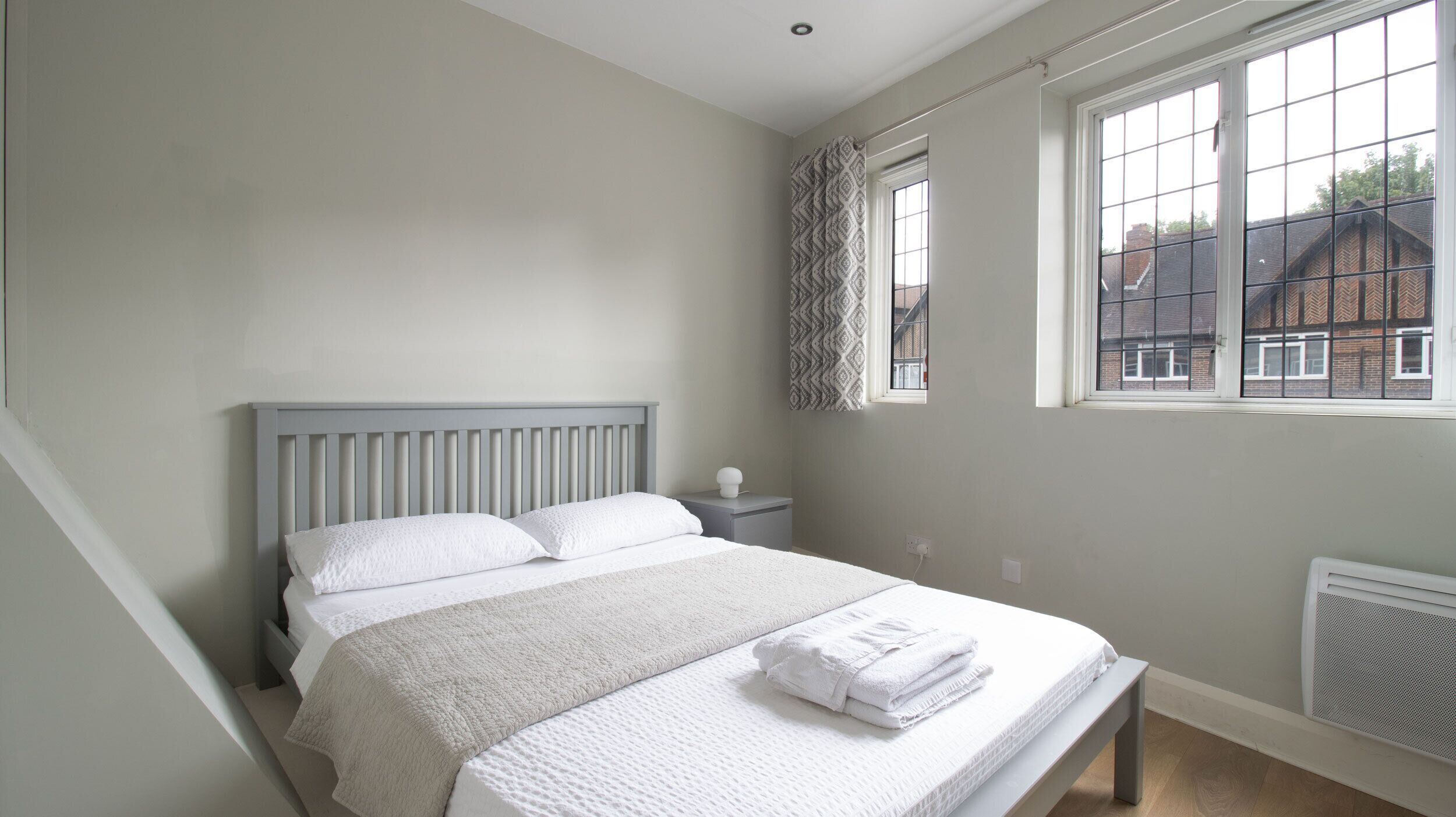 A bedroom with a bed, a nightstand, a window with a view, and a radiator.