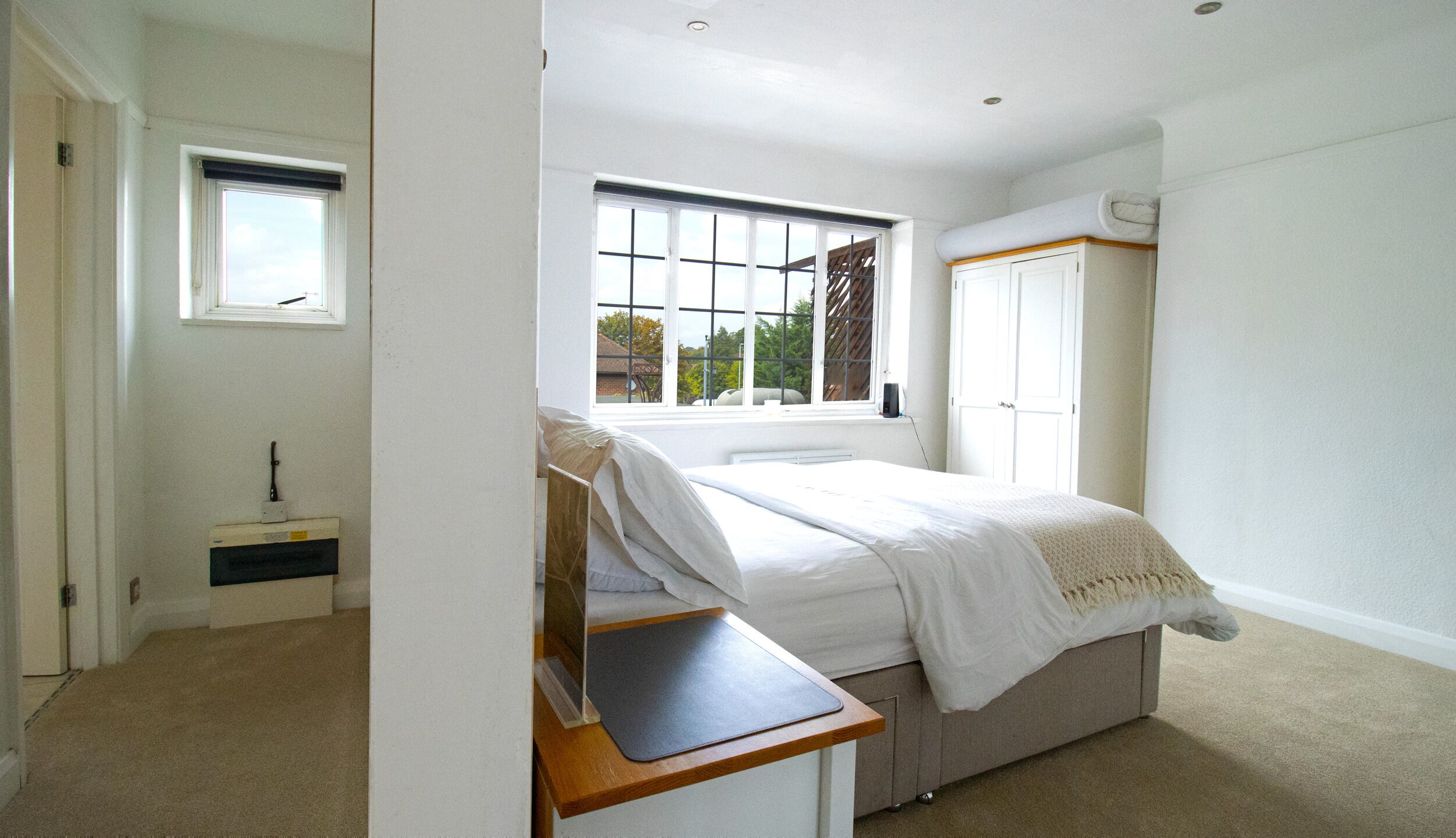 A bedroom with a bed, a window, a wardrobe, and a desk.