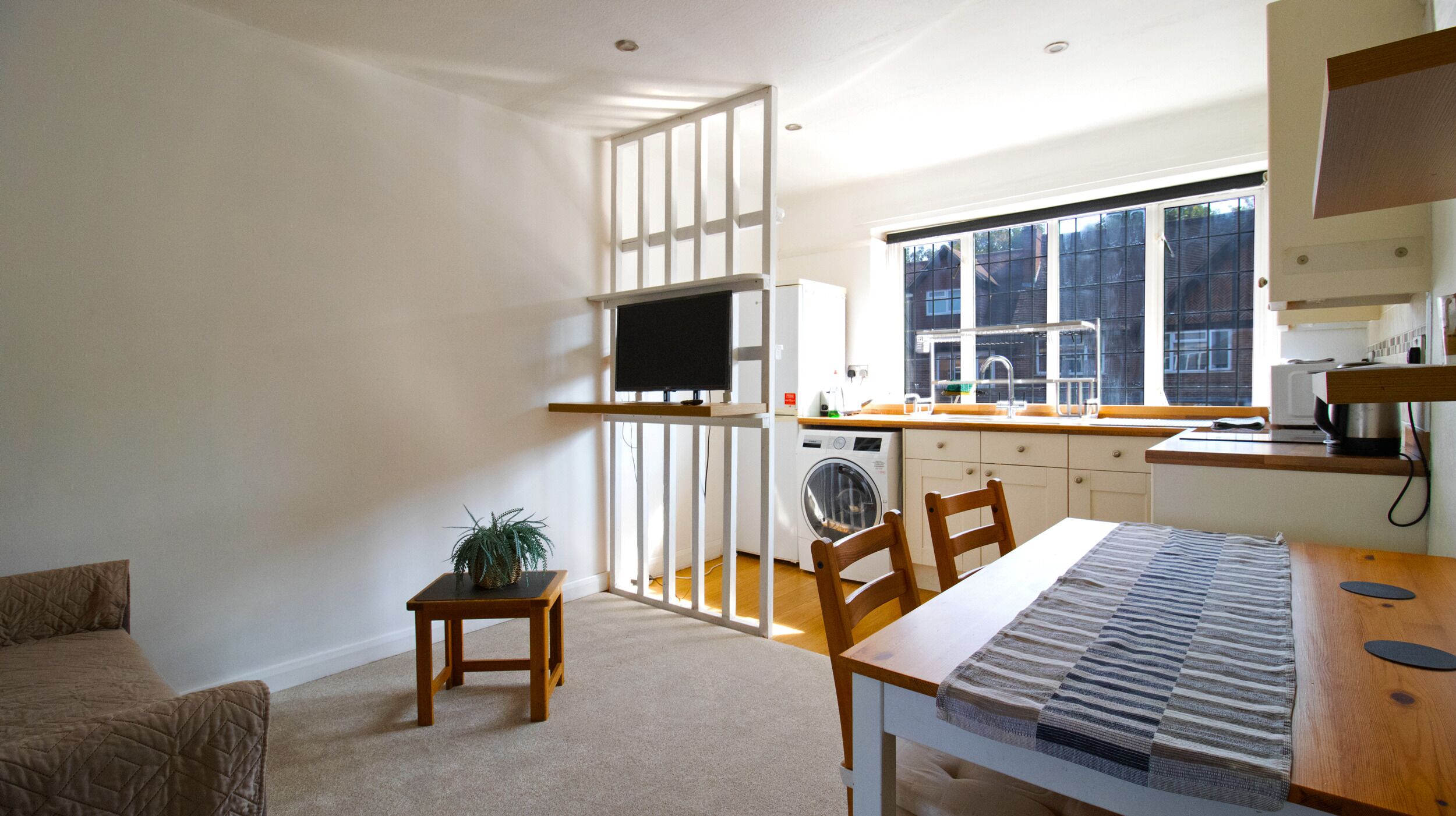 Un espacio habitable compacto con kitchenette, comedor y zona de estar.