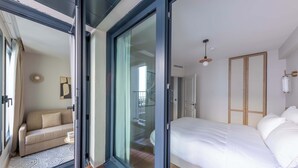 A bedroom with a bed, a sofa, and a sliding glass door leading to a balcony.