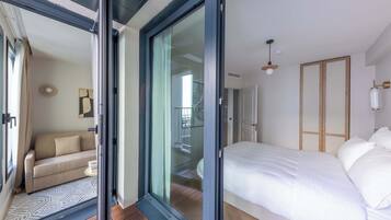 Un dormitorio con cama, sofá y puerta corrediza de vidrio que da a un balcón.