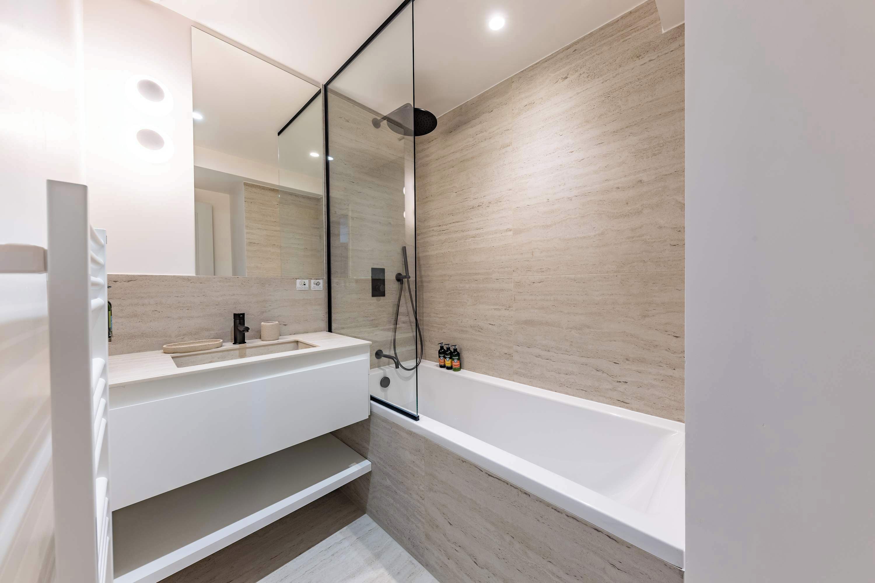 A modern bathroom with a glass-enclosed shower, a white vanity, and a bathtub.