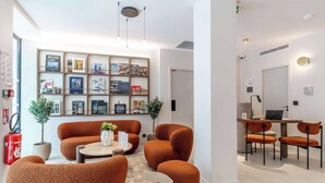 A modern living room with a sofa set, a coffee table, and a bookshelf filled with books and framed pictures.