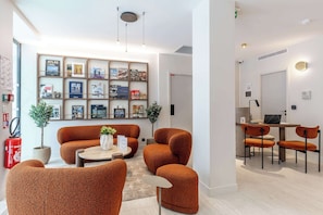 Een moderne woonkamer met een zithoek, een salontafel en een boekenkast vol boeken en ingelijste foto's.