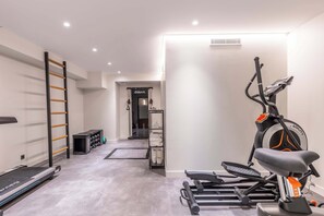 A home gym with a treadmill, elliptical, and weight rack. - Opera -3 Bedroom / 2 living rooms connecting apt. (Paris)