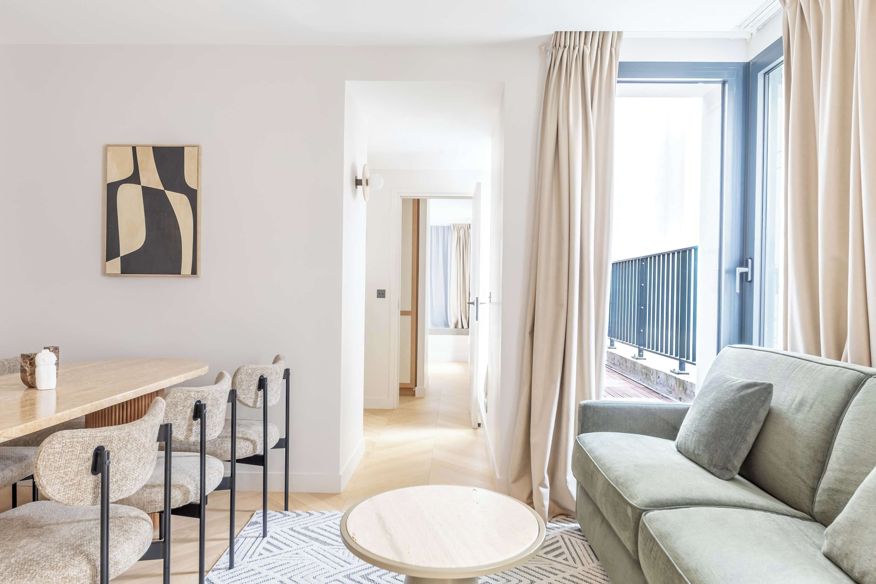 Ein modernes Wohnzimmer mit einer Couch, einem runden Couchtisch und einem Essbereich mit Stühlen und einem Tisch.