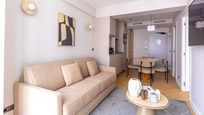 A modern living room with a beige sofa, a dining table, and a kitchen in the background.