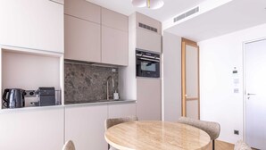 Une cuisine moderne dotée d’appareils électroménagers intégrés, une table de salle à manger ronde avec des chaises et une porte blanche.