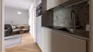 A modern kitchen with a stone backsplash, stainless steel appliances, and a dining area with a round table and chairs.