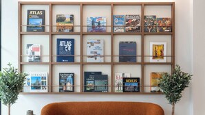 A modern living room with a sofa, a round coffee table, and a bookshelf with travel books. - Opera - Two Bedroom Balcony (Paris)