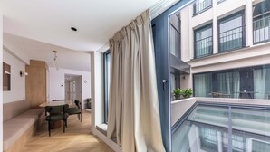 A modern apartment with a dining area, a balcony with a view, and a large window with curtains. - Opera - Two Bedroom Balcony (Paris)