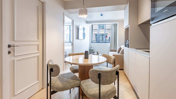 A modern kitchen with a built-in oven and a dining area with a round table and chairs. - Opera - One Bedroom in Paris (Paris)