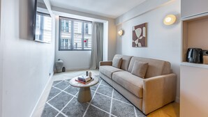 A modern living room with a sofa, a coffee table, a flat-screen TV, and a window with curtains. - Opera - One Bedroom in Paris (Paris)