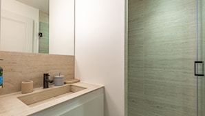 A modern bathroom with a beige countertop, a mirror, a sink, and a shower area. - Opera - One Bedroom in Paris (Paris)