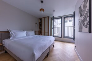 Un dormitorio con una cama grande, suelo de madera, un armario y una ventana con vistas.