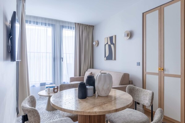 Een moderne woonkamer met een ronde salontafel, een beige bank en een aan de muur bevestigde televisie.