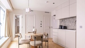 Une cuisine moderne avec des meubles blancs, une table de salle à manger ronde et une fenêtre avec des rideaux.